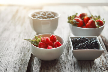 Bowls, berries and health on table, kitchen and organic choice for nutrition, breakfast and salad for wellness. Fruits, raspberry and mulberry in home with container, meal prep and food in morning