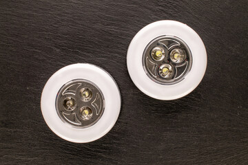 Naklejka premium Two battery-powered lanterns on slate stone, macro, top view.
