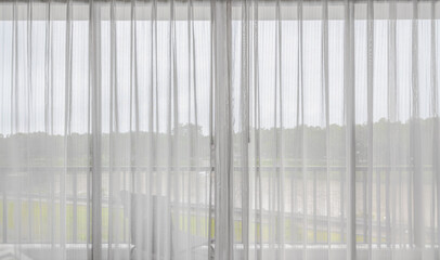 Interior of empty living room with large bright window and white curtains