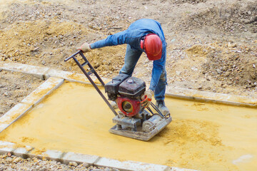 An unrecognizable worker using a floor leveling machine at a construction site.
