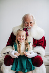 Santa with a smiling young girl in green dress, close-up, minima