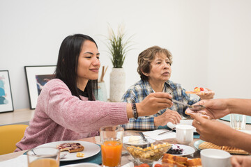 Mature mother and young daughter eating breakfast together at home