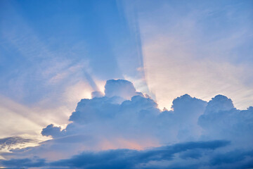 Low angle view of sunlight streaming through clouds in sunset