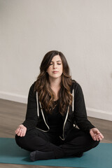 Women sitting in yoga possition on mat with eyes closed