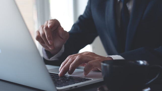Businessman working on laptop computer at modern office on table, closeup. Business man typing on laptop, searhing the information, internet networking, corporate business