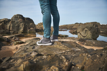 Person standing on rocky shore by the sea during daytime
