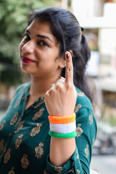 Smart young lady showing her ink-marked fingers after casting votes in front of polling booth of east Delhi area for general Lok Sabha Elections 2024