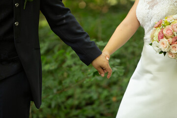 Groom and bride holding hands with wedding dress and bouquet of flowers