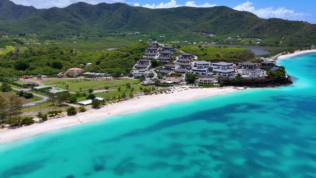 Establishing aerial view of the beautiful Ffryes Beach at the Caribbean island of Antigua with turquoise sea and tropical forest