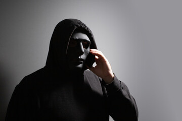 Phone Scammers, man in a mask with a phone, criminal network stealing data, hacker breaking into...