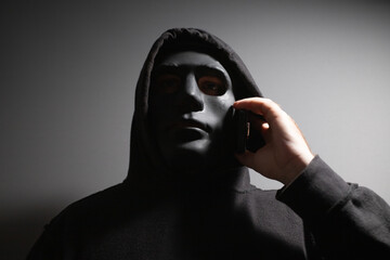 Robber, a man in a mask talking on the phone, dangerous felon strategizing, violence and theft...