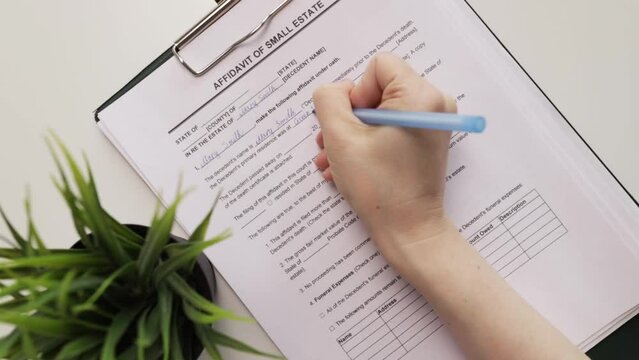 Affidavit of small estate, hand fills out a document, insurance policy, real estate purchase, financial security.
