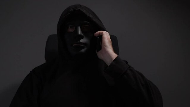 A man in a mask talking on the phone, spy handling secret information, fake identity being used, dark scheme being executed.