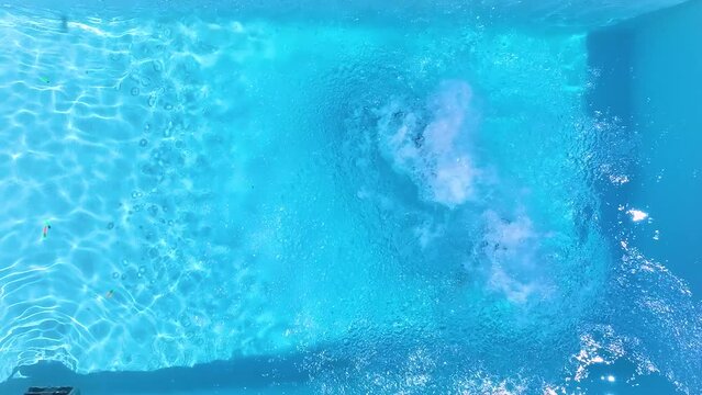 Slow motion overhead view of a holiday couple jumping together into the swimming pool, background of a summer concept