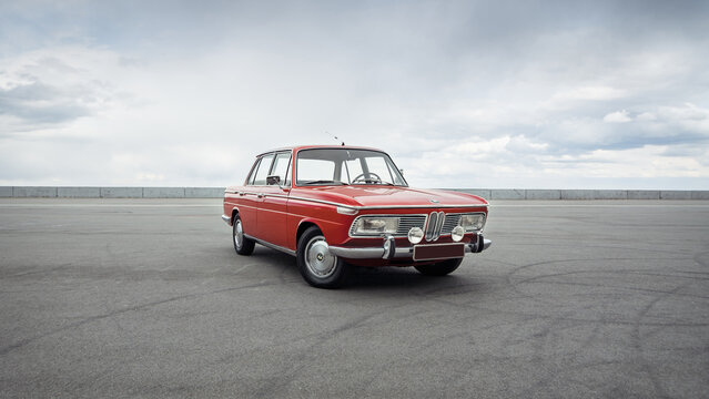 Red classic BMW from 1960s. Three quarter view of german sedan in front of cloudy sky. Vyshhorod, Ukraine - April 18 2015.