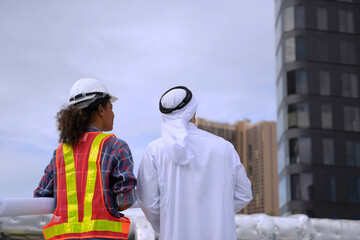 Middle eastern man and African woman are working together on rooftop.