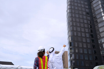 Middle eastern man and African woman are working together on rooftop.
