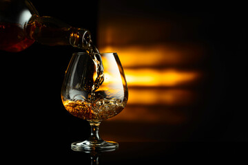 Pouring brandy from a bottle into a snifter.