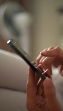 Vertical cropped shot of unrecognizable gamer male clicking fingers on mobile phone screen to farming new Hamster Kombat crypto coin in online application. Shooting in slow motion.