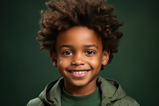 Portrait of a little afro boy with afro curls in green on a green background, portrait of a happy child.