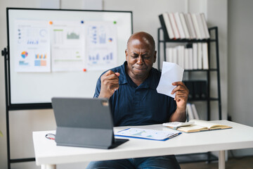 Naklejka premium Businessman Celebrating Success at Work Desk with Laptop and Documents in Modern Office Setting