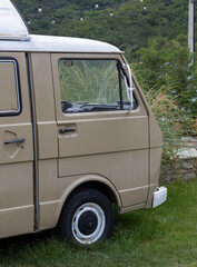 Vintage beige camper van parked on lush green grass with string lights above, capturing a peaceful, scenic outdoor setting. Perfect for outdoor adventure, travel, and nostalgia themes.