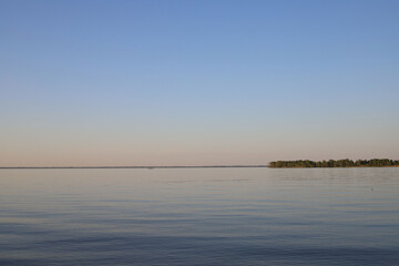 panorama of a river or lake. evening. outlines of trees in the distance. bluish-orange sky