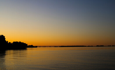 Fototapeta premium sunset. silhouette of trees and bridge against the background of an orange sunset