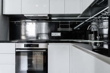 modern minimalist black and white kitchen.  Kitchen with built-in kitchen appliances, microwave, oven, refrigerator. The countertop and dining area in the kitchen are made of black stone.