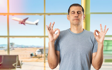 Caucasian man at airport relax and smiling with eyes closed doing meditation gesture with fingers...