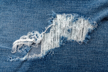Hole in jeans close-up. Texture of faded denim