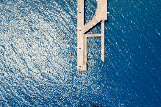 Aerial view of wooden pier stretching into sparkling blue ocean water. Limassol, Cyprus