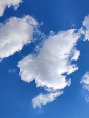 White clouds and blue sky. Bright colorful picture for the decoration of stretch ceiling, printing, wallpaper.  Vertical photo