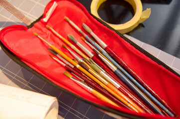 Collection of paintbrushes in red case on work table in art workshop