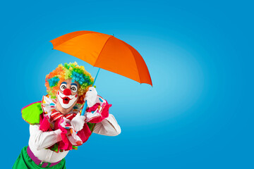 Surprised clown holding umbrella. Entertainer Joker in colorful suit and wig. Buffoon with clown...