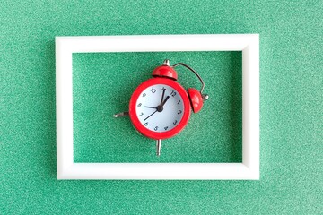 Alarm clock and white photo frame on color background. Minimal concept