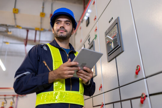 Electrical engineer inspect relay protection system with laptop tablet computer. Electrician factory worker working with Bay control unit in container construction site. High voltage switchgear. - Powered by Adobe