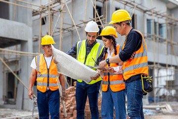 Foreman, engineer or architect with safety helmet holding laptop and blueprints for inspection details on construction in a new real estate construction site with crane and mechanical equipments.