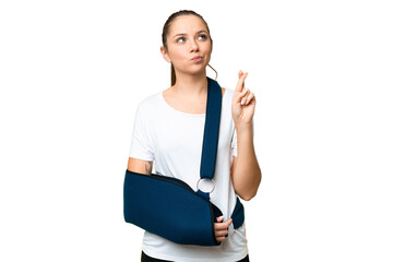 Young blonde woman with broken arm and wearing a sling over isolated chroma key background with...