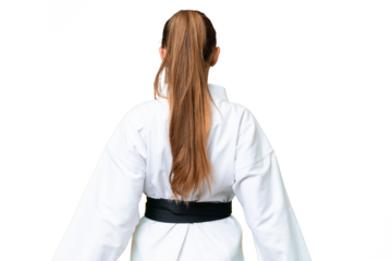 Young blonde woman over isolated chroma key background doing karate in back position