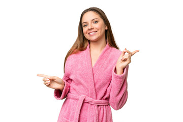 Young woman in a bathrobe over isolated chroma key background pointing finger to the laterals and happy