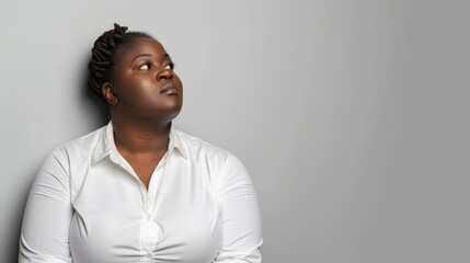 Obraz premium A woman in a white blouse looks up with a contemplative expression