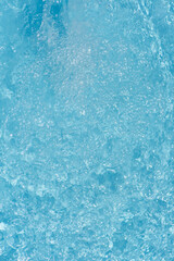 Blue water with ripples on the surface. Defocus blurred transparent blue colored clear calm water surface texture with splashes and bubbles. Water waves with shining pattern texture background.