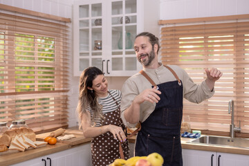 Cheerful, sunny kitchen scene with lively atmosphere where couple playfully interacts with fruits.