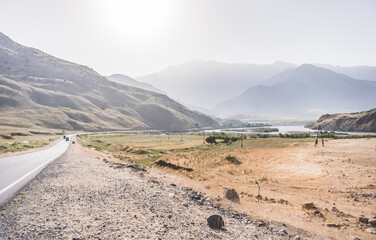 Automobile asphalt road in the mountains in the valley between rocky mountains, Pamir Highway in Tajikistan