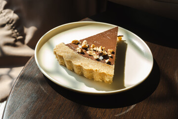 A slice of chocolate cake with walnuts on top of a white plate