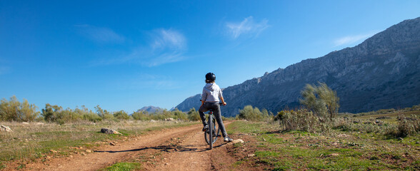Young boy on mountain bike on a road with mountain