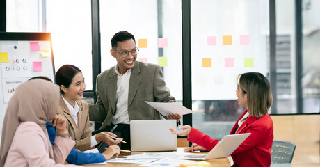 Diverse  executive business partners group discuss report at boardroom meeting table.