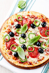 Pizza with salami, jalapeno pepper and black olives. Home made food. Concept for a tasty and hearty meal. Close up.	