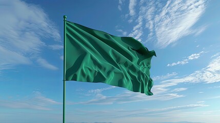 Green flag waving in the wind against a blue sky with clouds. Symbolic and patriotic imagery for various themes and occasions.